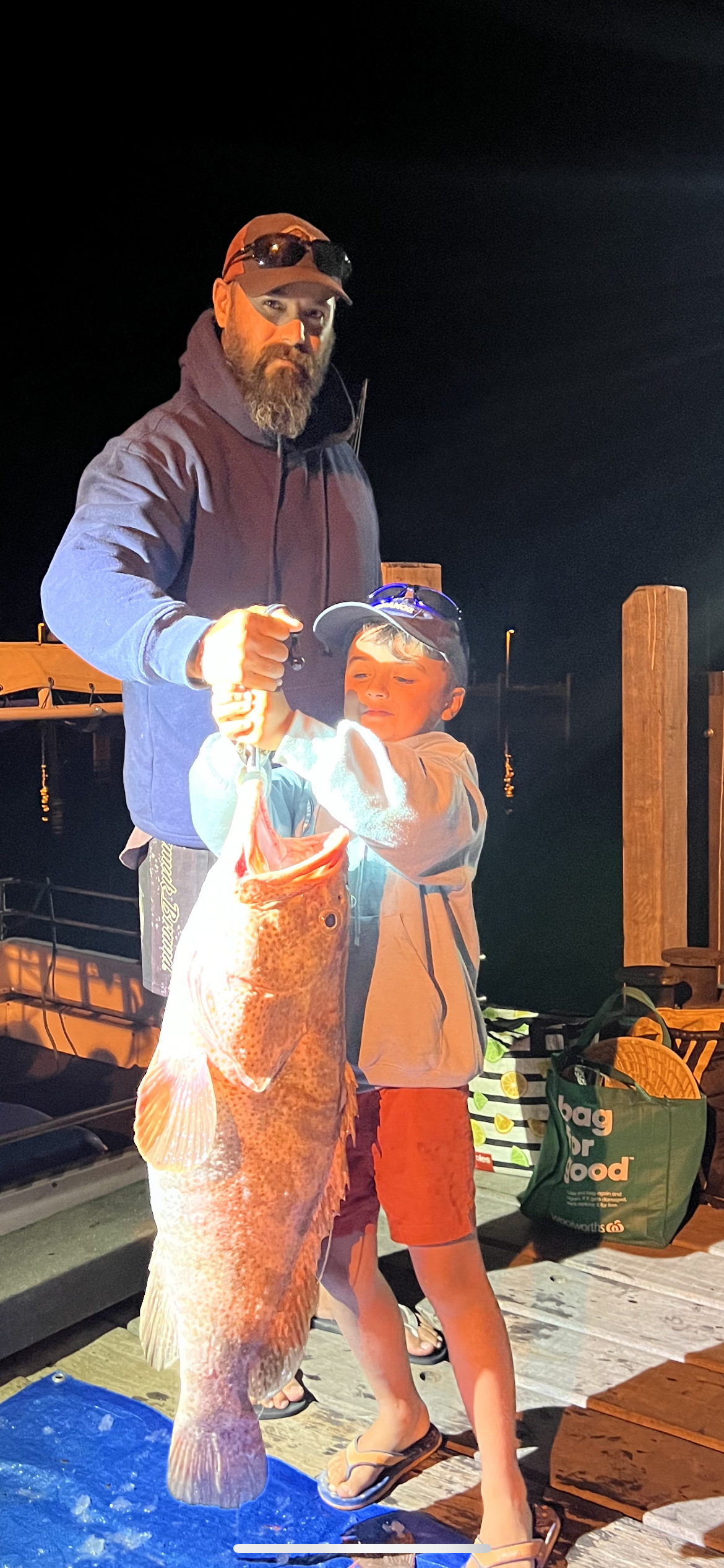 Child and Glenn holding a fish at night