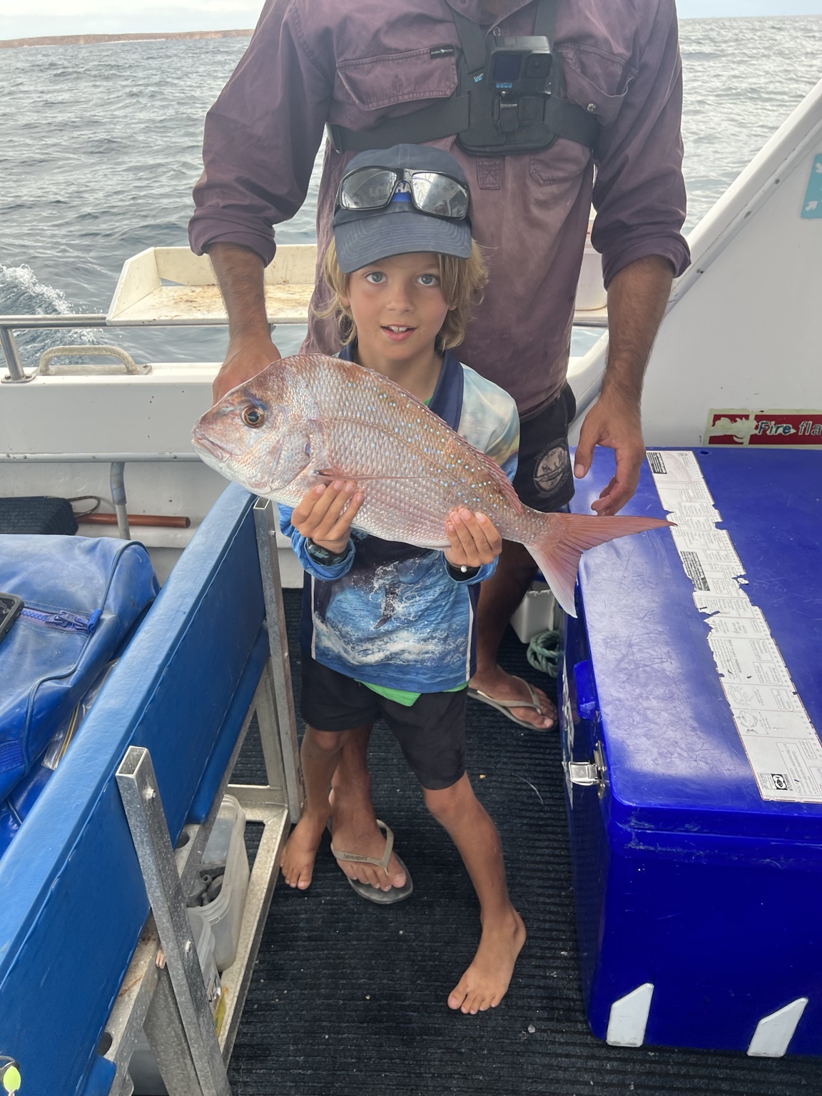 Child holding a snapper on a boat